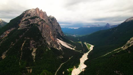 top aerial view of dense trees and road in dolomite mountain range in italy