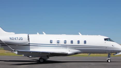 a jet taxis in front of a private jet on a parking pad at an airfield in deer lodge montana