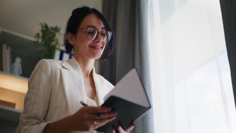 Joyful-Smiling-Businesswoman-Writing-in-Notebook