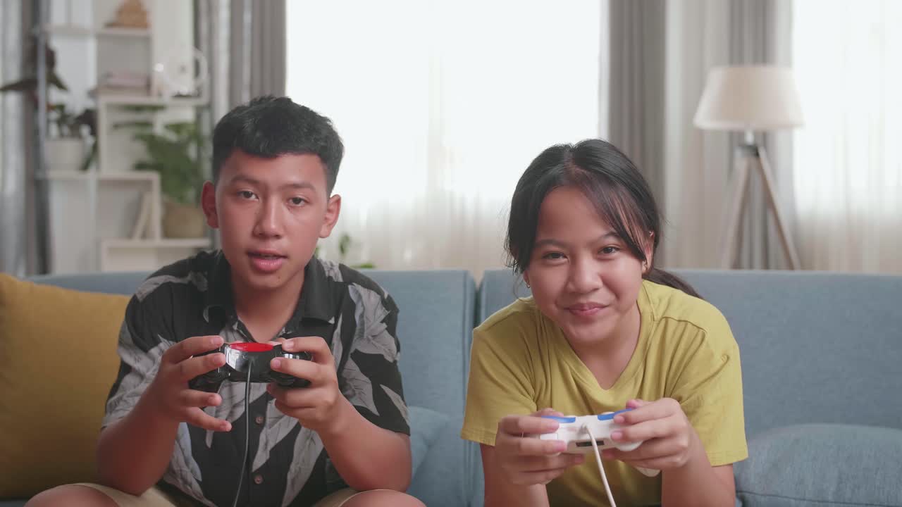 เด็กชาวเอเชียพร้อมจอยสติ๊กเกมกำลังเล่นวิดีโอเกมที่บ้าน