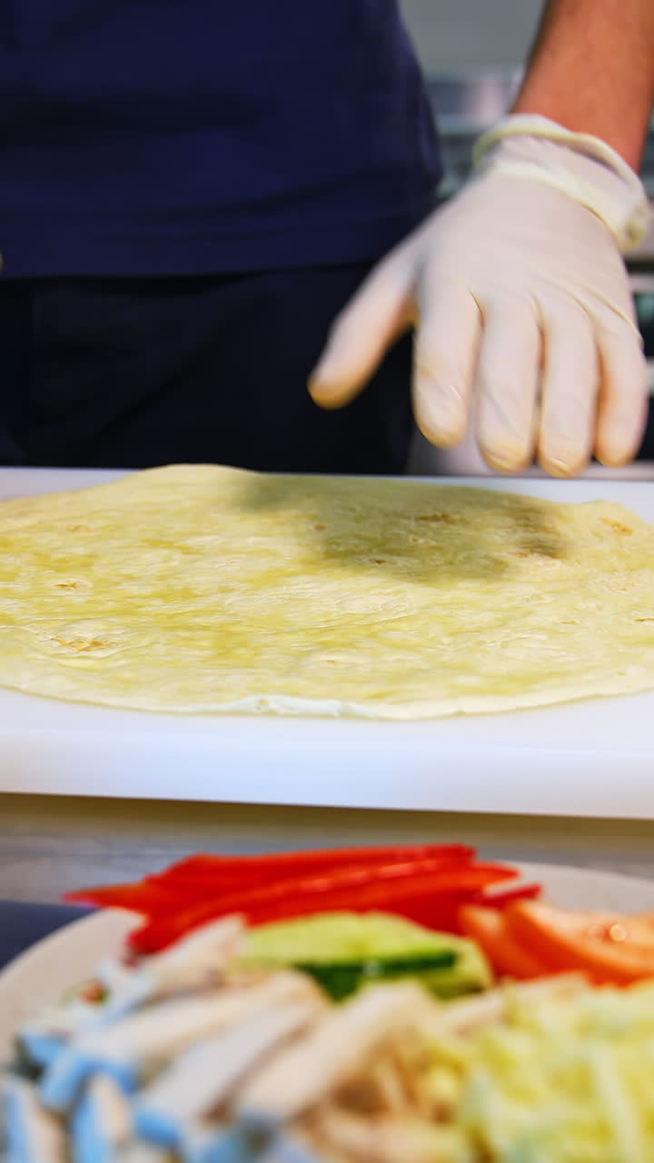 Pita on a table. Man`s hands put white souce on a top. Place with ingredients stand at side. Tasty junk food. Vertical video