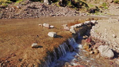el río fluye a través de un camino de tierra en las montañas del alto atlas, marruecos