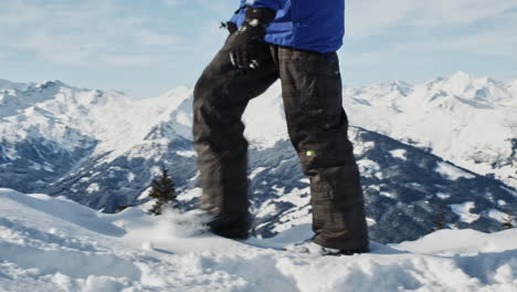 Person-in-snowboard-outfit-walking-through-the-snowdrift-in-the-alpine-scenery