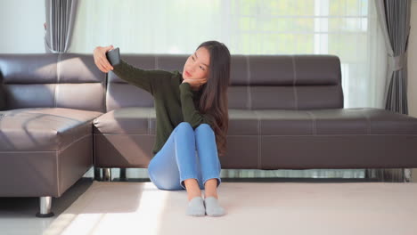 a pretty woman sitting on the floor tries several angles for just the right selfie