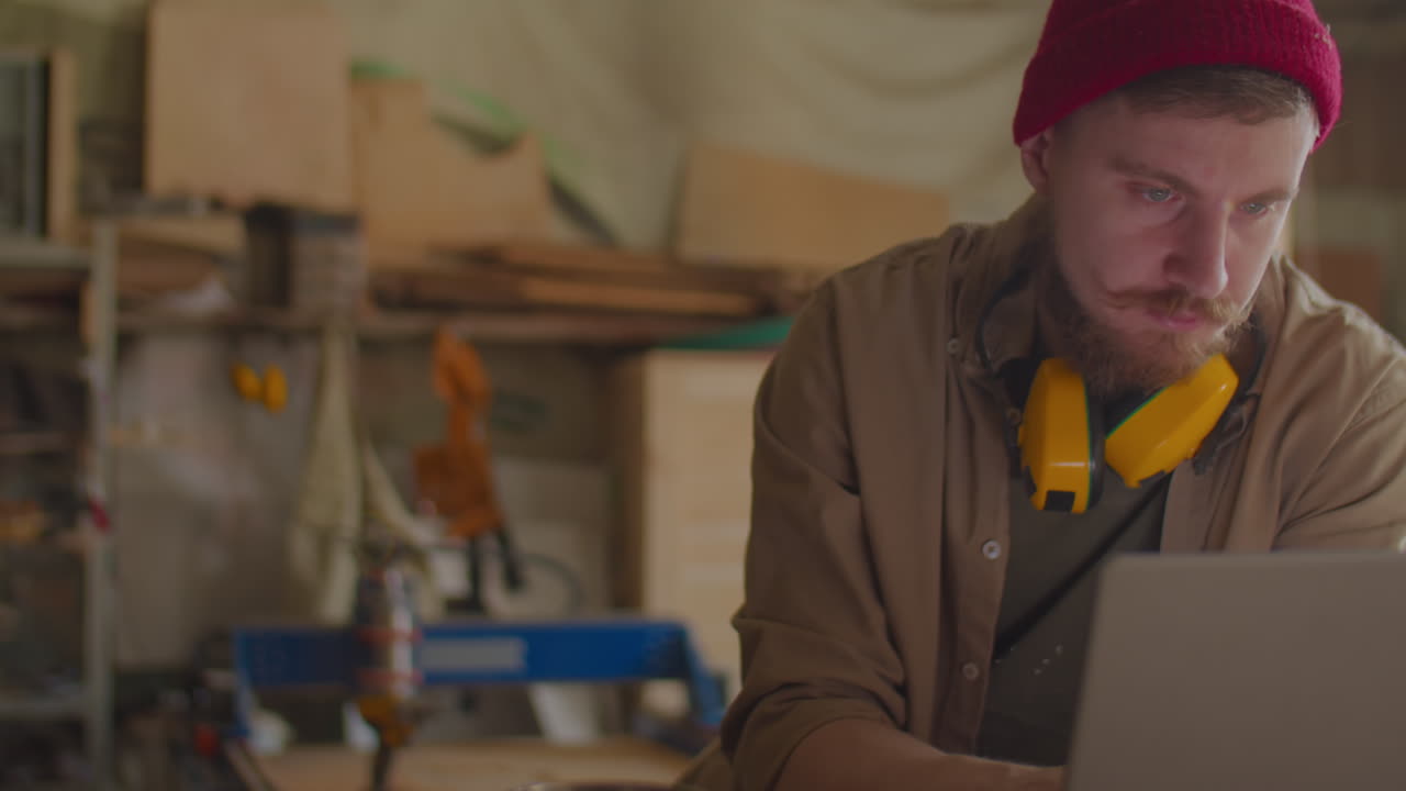 Carpenter Using Laptop in Workshop