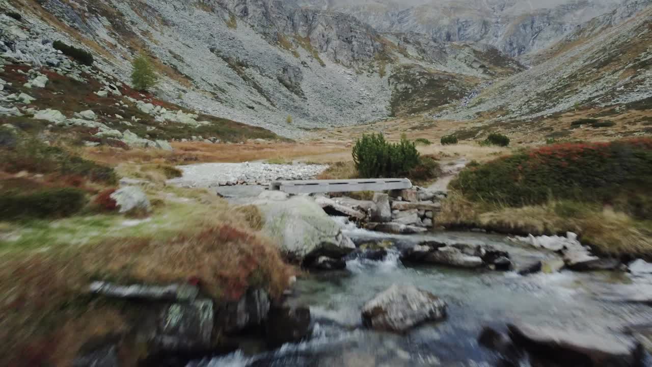 Rushing waterfall cascading over rocky terrain with rugged mountain backdrop