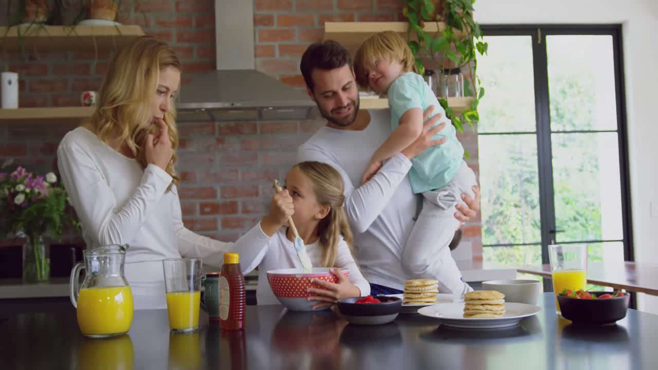Famiglia che prepara il cibo sul piano di lavoro in cucina in una casa confortevole 4k