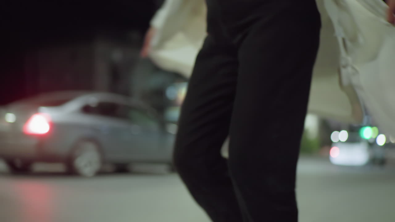 Excited young girl turns around joyfully with floating white coat in motion, captured against illuminated urban background during night time, expressing freedom