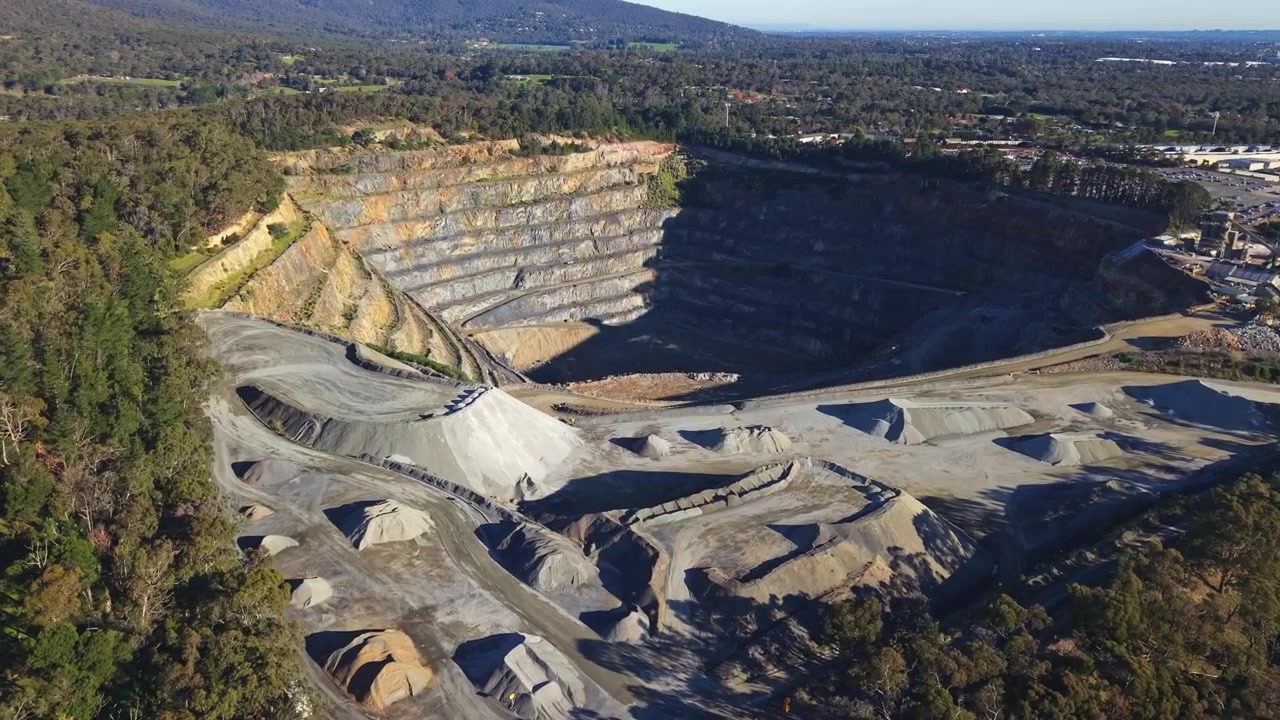 Spettacolare video drone della Cava di Montrose a Melbourne con vaste pareti rocciose terrazzate, cumuli rocciosi e macchinari sotto la luce chiara del giorno. Riprese aeree di un paesaggio industriale e dinamico