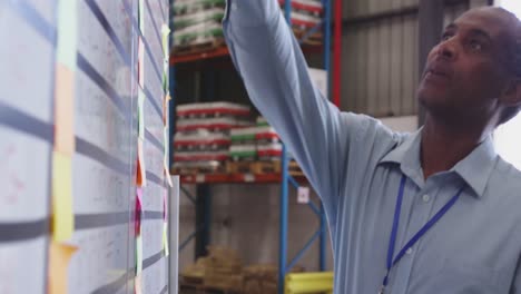 Close-of-man-writing-on-clipboard-in-warehouse-4k