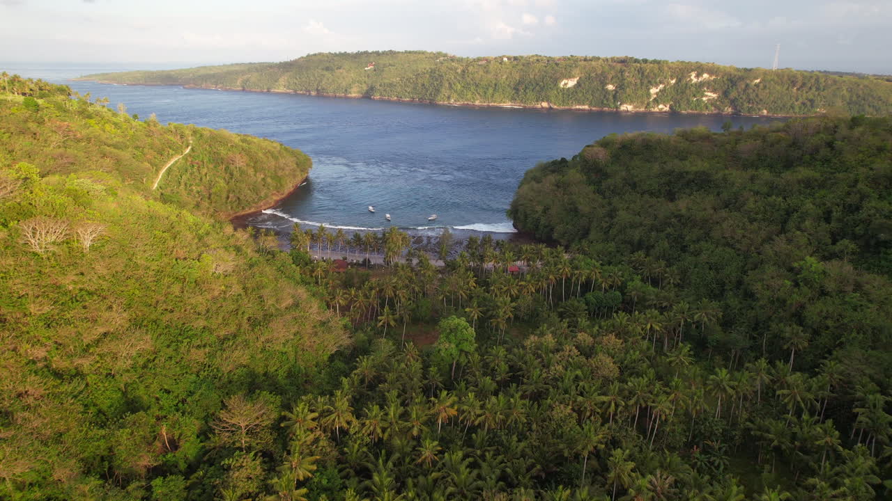 인도네시아 발리 누사 페니다 의 가마트 만 해변 을 드러내는 언덕 에 있는 열대 숲 위 를 날아다니는 공중 의 일출