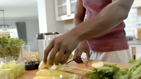 midsection of african american man preparing healthy smoothie in kitchen at home, slow motion