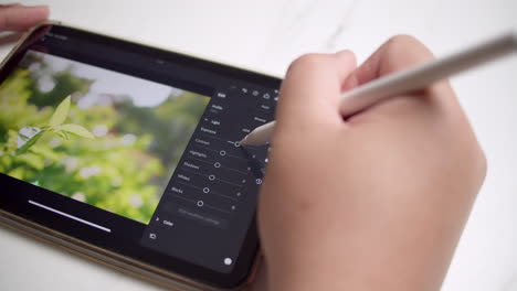 ediciones en una tableta con una herramienta de pluma blanca en el ajuste de colores e iluminación de una imagen de planta verde vibrante