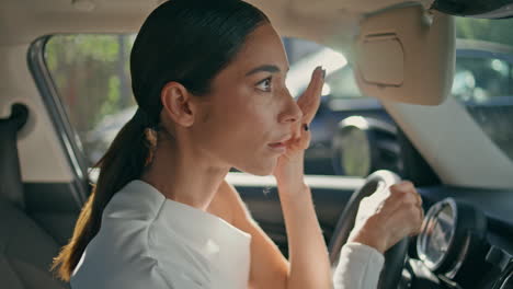 brunette looking car mirror sitting front seat close up. woman looking camera