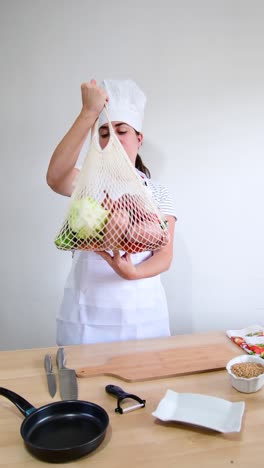 female cook holding string bag with fresh vegetables.