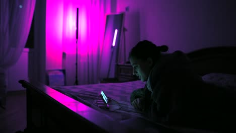 mujer acostada en la cama por la noche, mirando el teléfono