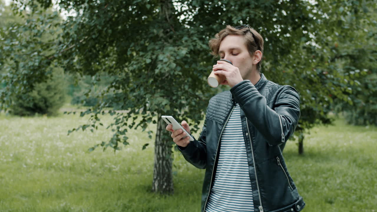 Man Drinking Coffee and Using Phone in Park