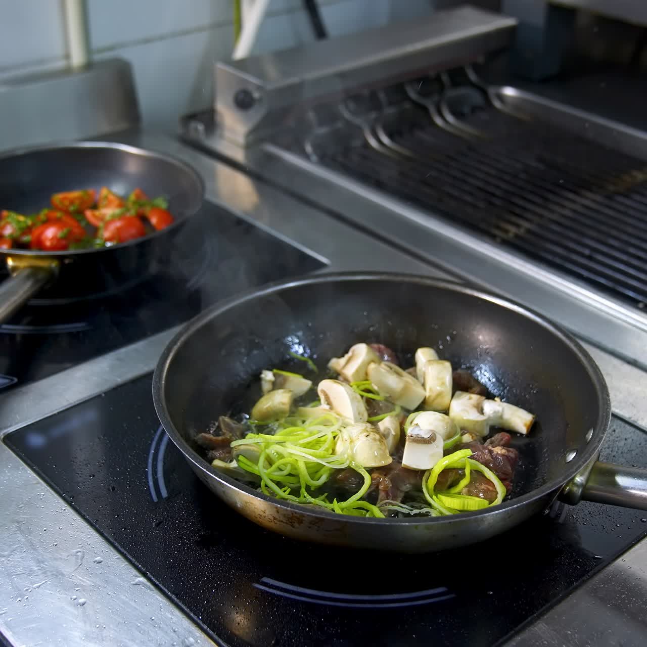 Cooking food in frying pans. Chef pouring sauce into the frying mushrooms. Making fried mixed vegetable with sauce in metal pan in the restaurant kitchen