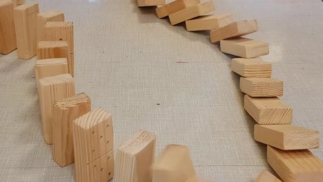 Close-up-view-of-falling-wooden-domino-pieces-in-a-circle-on-a-table