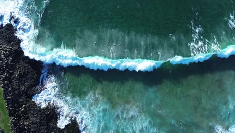 drone aerial landscape birds-eye shot of surfers duck dive paddle out line-up ocean waves swell rocky headland ocean floor sand bar kiama beach travel tourism nsw australia south coast 4k