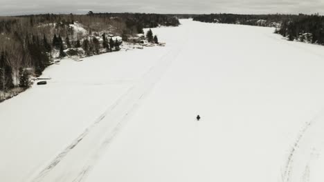 una moto de nieve viaja a lo largo de un lago congelado en el ártico de canadá