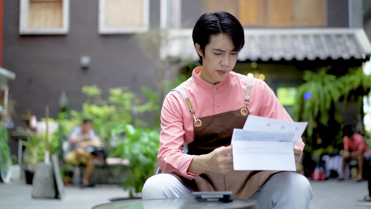 지루하고 불안한 아시아 남성 소규모 사업주 소득과 지출을 계산하고 비용을 확인하는 커피 잠금 기간 동안 그는 피곤하고 힘들고 화가 나 현금 손실 또는 대출