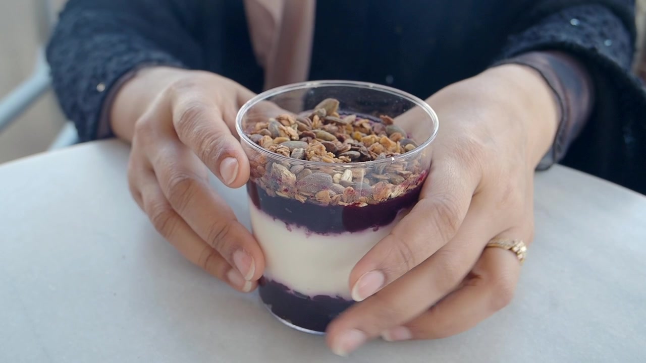 Persona che tiene in mano un parfait di yogurt a strati con granola