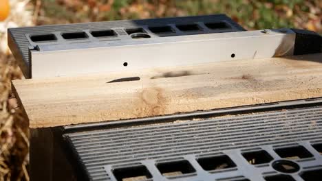 Cedar-Wooden-Board-Being-Pushed-Through-a-Metal-Table-Saw-Outdoors,-Close-Up