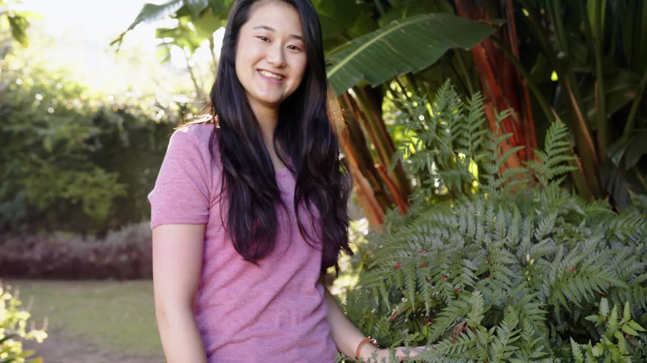 Woman looking up, touching fern, walking closer, magenta streak crossing woman for gardening