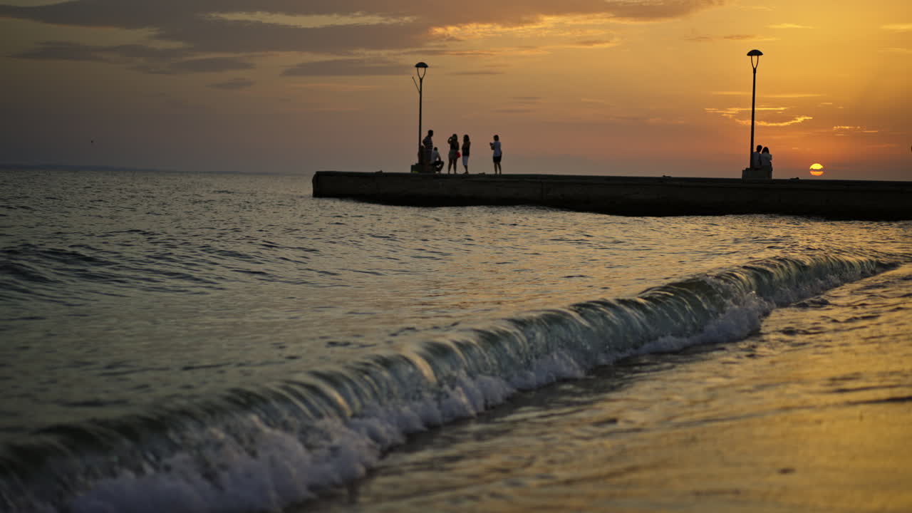 Sunset at the beach with people on pier