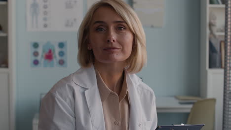 doctor in office writing on clipboard