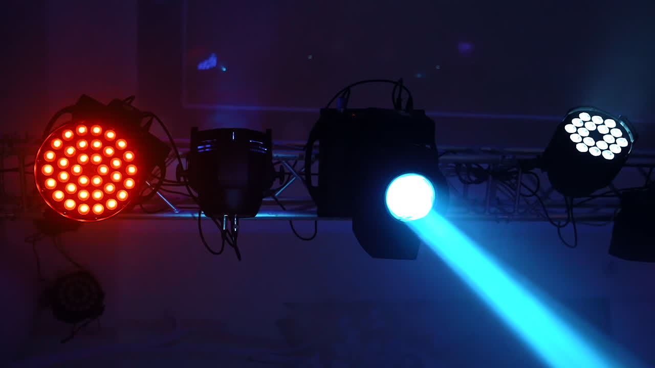 Lighting equipment flashing over the stage. Close-up spotlights with laser rays inside the disco club. Colorful lights in the modern hall glowing from the ceiling.