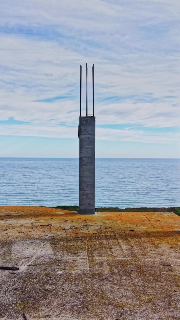 Byggeplads med udsigt over havet med betonpiller og armeringsjern