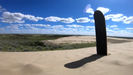 skateboard deck sitting in sand at the alberta sand dunes on a sunny day