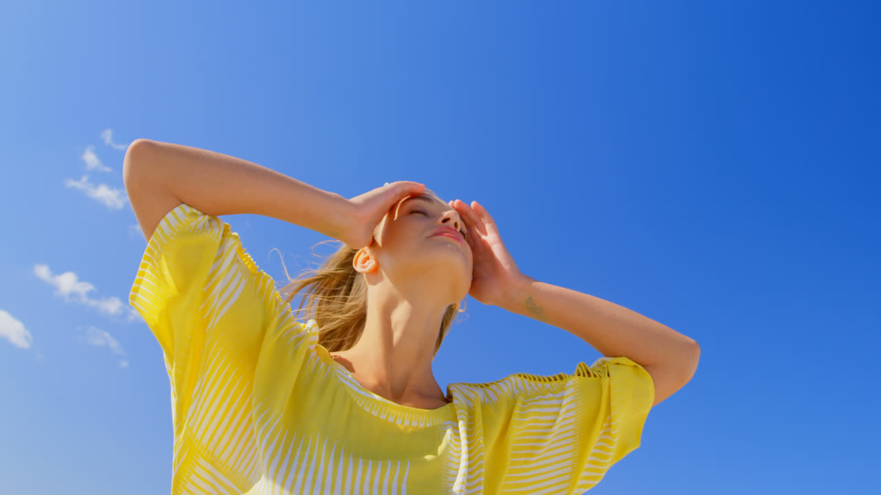 해변에 서 있는 젊은 백인 여성의 낮은 각도 뷰 4k