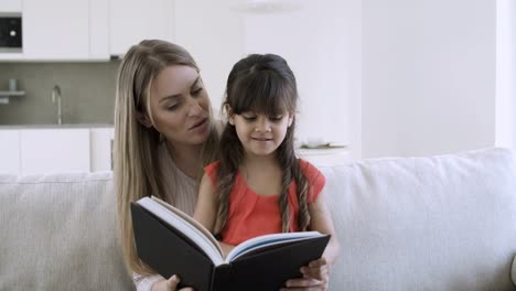 mom and her cute girl reading book together