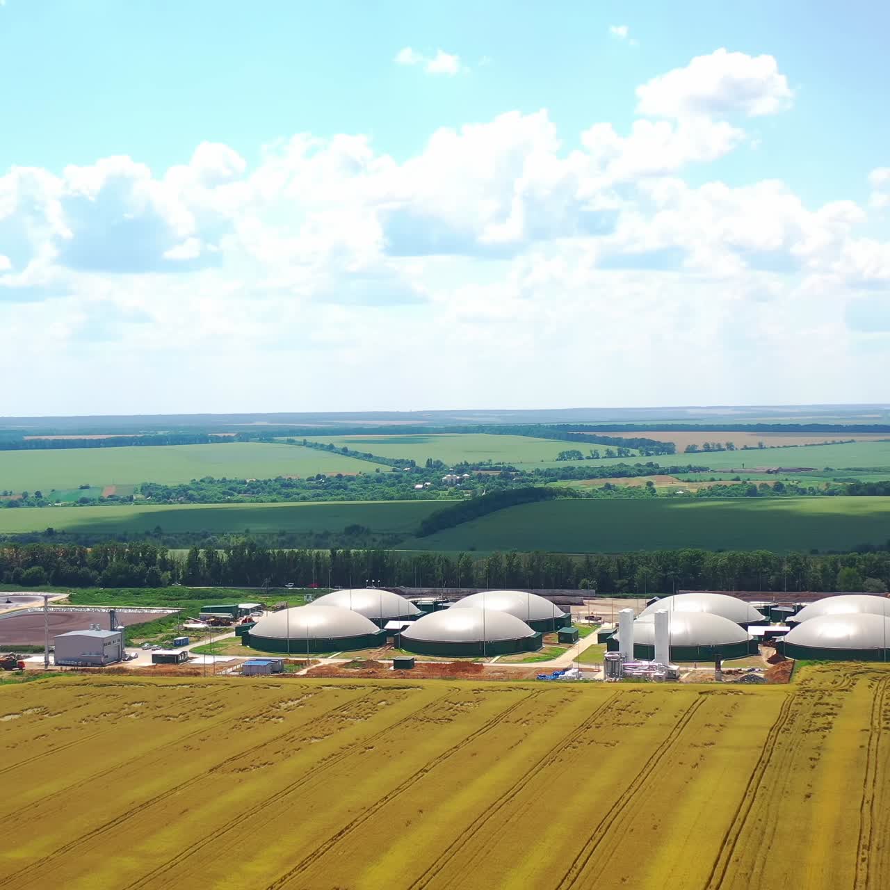 Modern bio farm surrounded by green nature. Innovative agriculture reservoirs for bio gas production on field in summer. Aerial view
