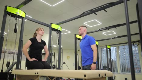 woman receiving physical therapy assistance from a personal trainer in a gym.
