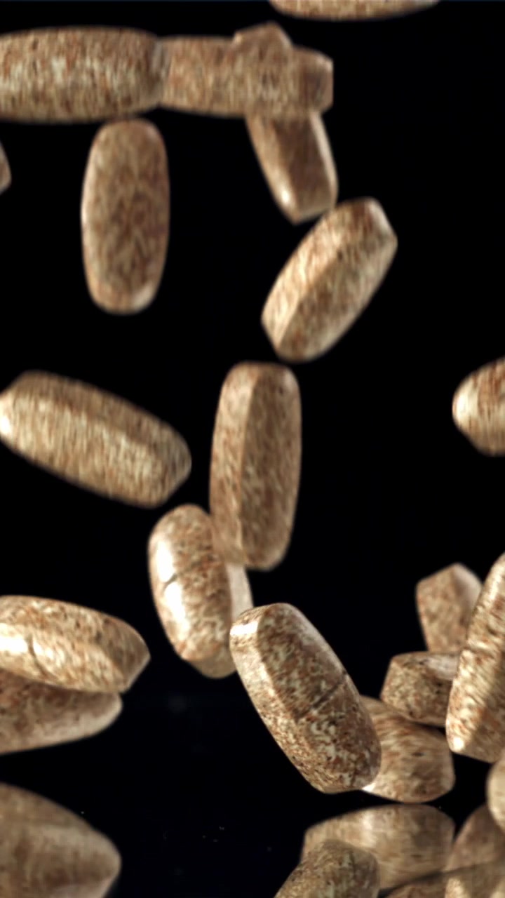 Brown Pills Falling in Slow Motion on Black Reflective Surface