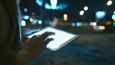 mujer usando el touch pad mientras camina por la ciudad por la noche