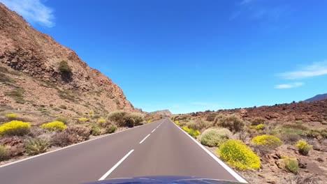 blue car on a straight road with blue sky and white clouds, desert landscape, driver point of view, fpv