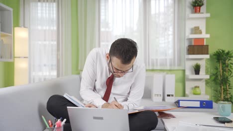 focused serious businessman working, looking at documents, working on laptop.