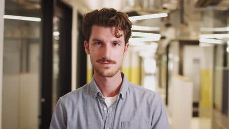 Millennial-white-man-standing-in-the-corridor-of-an-office-building,-close-up,-focus-on-foreground