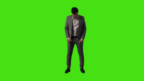 full length shot of businessman standing against green screen straightening and adjusting suit against green screen