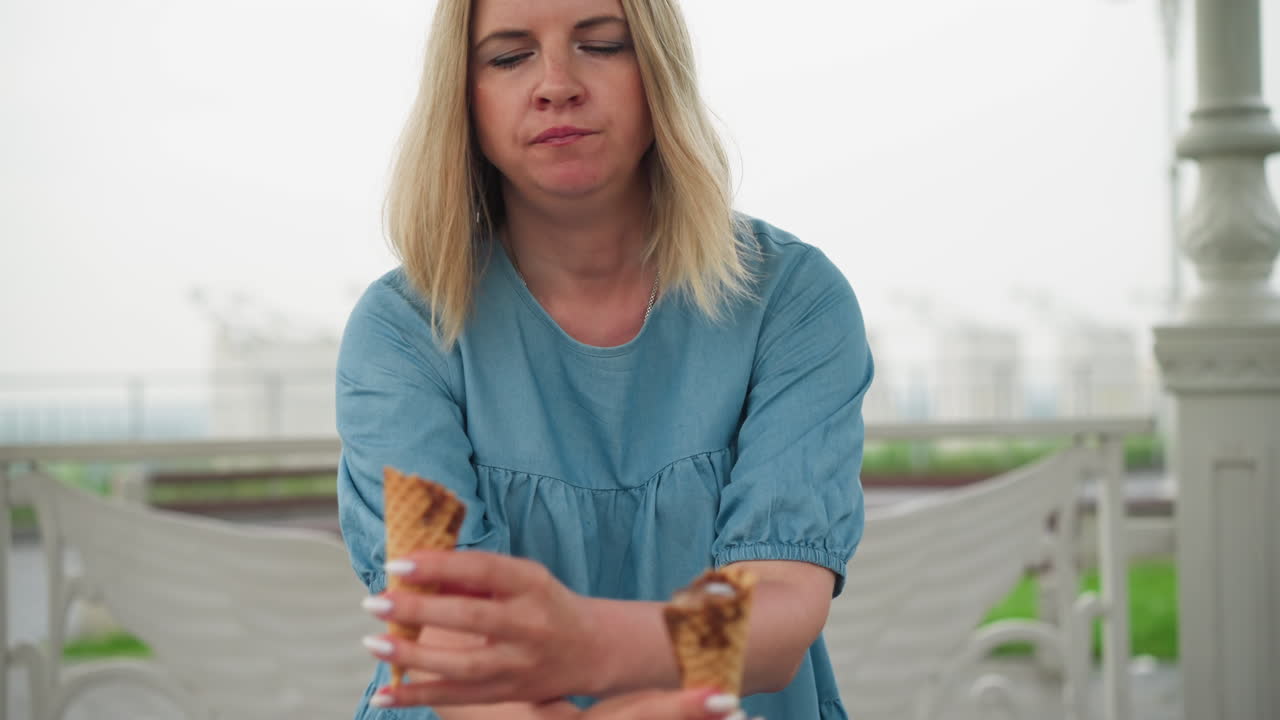 se ve a una madre sosteniendo dos conos de helado, sus manos cruzadas mientras se prepara para dar las golosinas a sus hijos, con los niños recogiéndolas de ella