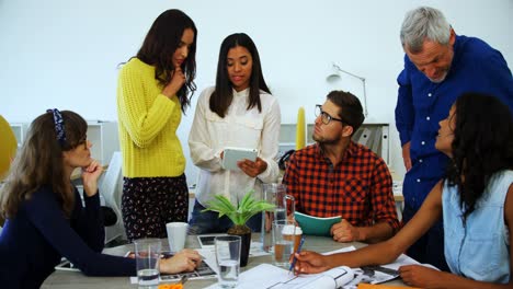 Executives-discussing-over-digital-tablet-in-office