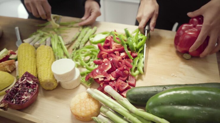 People chopping fresh vegetables in kitchen