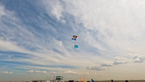 parachutists descend with flags under a vibrant sky during the avalon airshow in geelong, showcasing dynamic aerial maneuvers