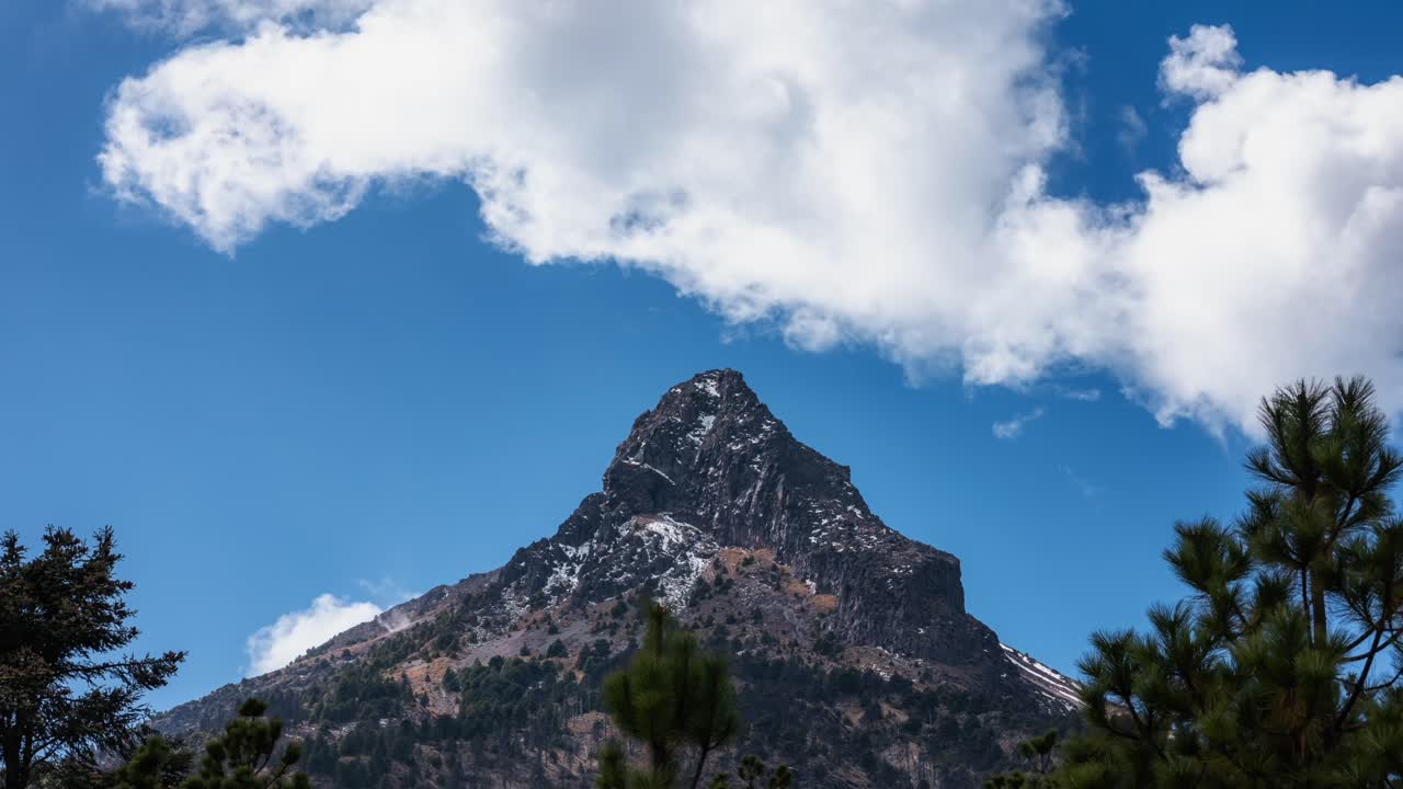 el lapso de tiempo de las nubes dinámicas sobre el pico de nevado de colima en un día soleado, estallidos de sol a través de las nube