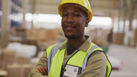 portrait of african american male worker wearing safety suit and smiling in warehouse